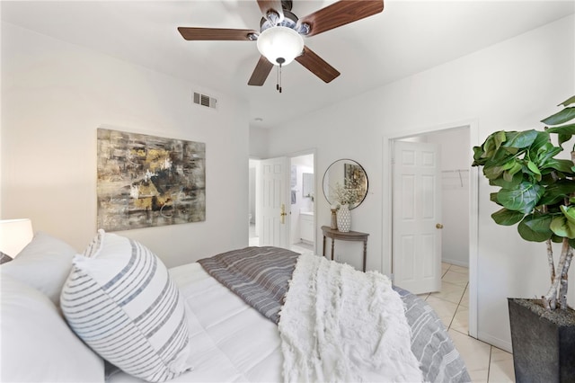 bedroom featuring ensuite bathroom, light tile patterned floors, visible vents, and a ceiling fan