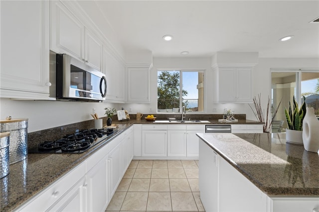 kitchen featuring light tile patterned flooring, white cabinetry, stainless steel microwave, and black gas stovetop