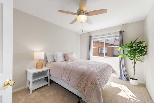 bedroom featuring light carpet, a ceiling fan, and baseboards