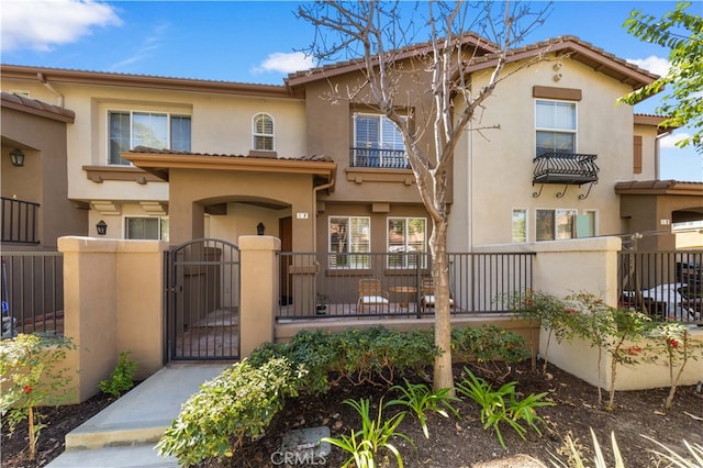 mediterranean / spanish-style house featuring a gate, a fenced front yard, and stucco siding