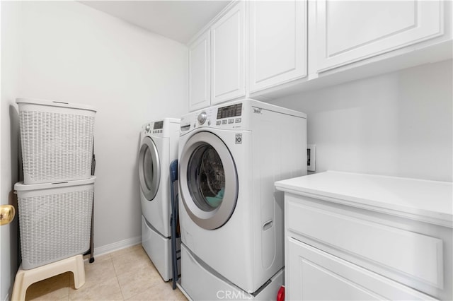 clothes washing area with washer and dryer, light tile patterned floors, cabinet space, and baseboards