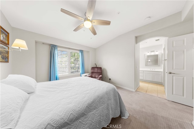 carpeted bedroom with a ceiling fan, connected bathroom, arched walkways, baseboards, and lofted ceiling