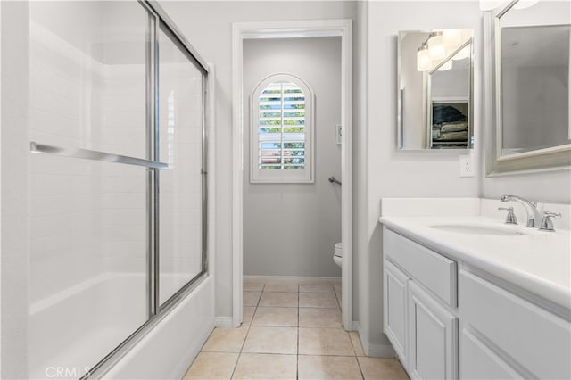 bathroom with tile patterned floors, toilet, combined bath / shower with glass door, baseboards, and vanity