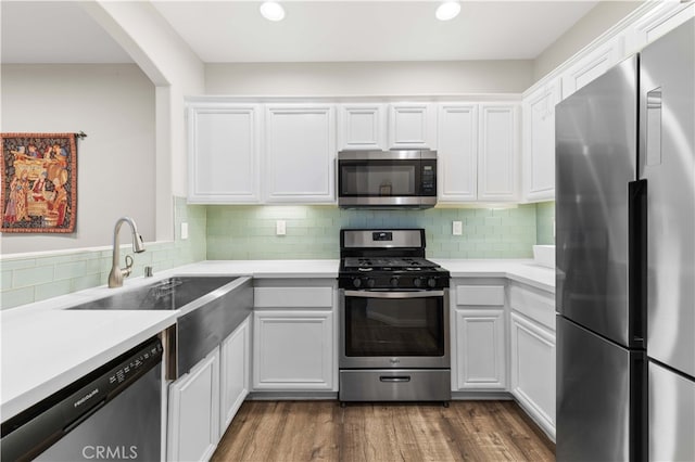 kitchen with a sink, dark wood finished floors, white cabinetry, appliances with stainless steel finishes, and light countertops