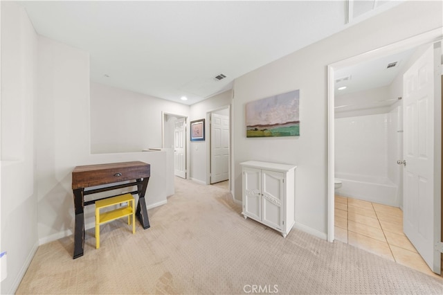 corridor featuring visible vents, baseboards, light colored carpet, and light tile patterned flooring