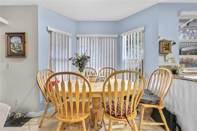 dining area featuring a textured ceiling, tile patterned flooring, and baseboards