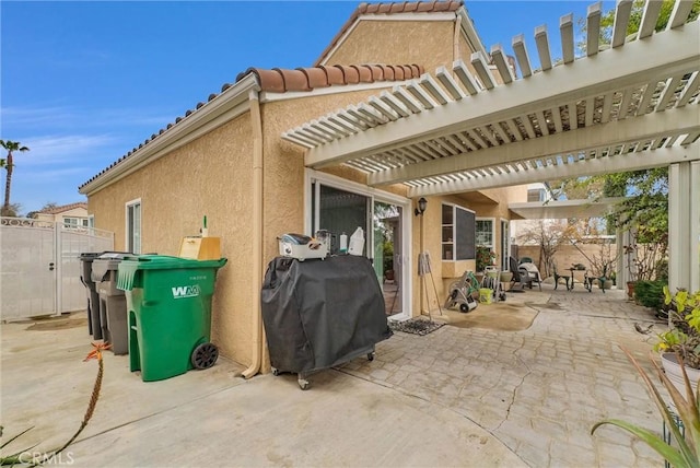 view of patio with area for grilling, fence, and a pergola