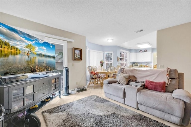 living area with light tile patterned floors, a textured ceiling, and visible vents