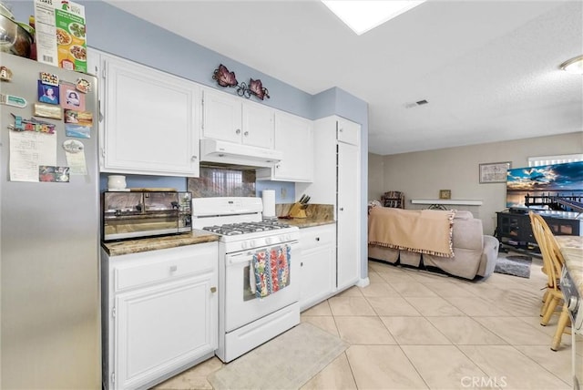 kitchen with under cabinet range hood, white cabinetry, open floor plan, white gas range oven, and freestanding refrigerator