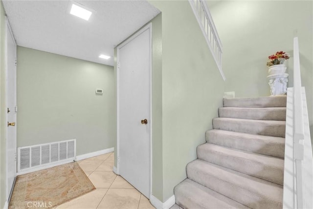 stairs featuring baseboards, visible vents, and tile patterned floors