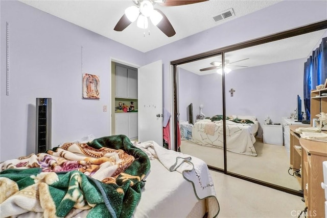 carpeted bedroom with a closet, visible vents, and ceiling fan