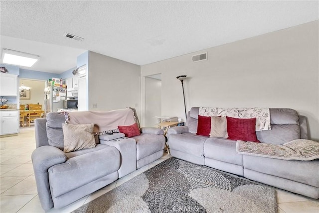 living area featuring visible vents, a textured ceiling, and light tile patterned flooring