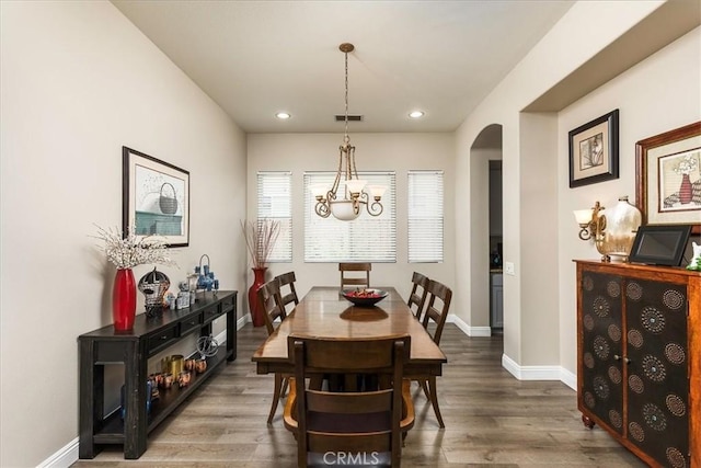 dining space with arched walkways, visible vents, baseboards, and wood finished floors