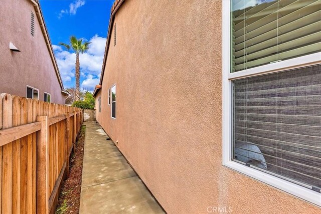 view of side of property with fence and stucco siding