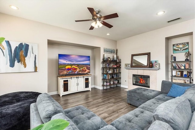 living area featuring recessed lighting, visible vents, a tiled fireplace, wood finished floors, and baseboards