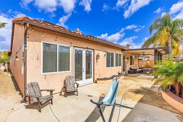 rear view of property featuring french doors, a patio area, fence, and stucco siding