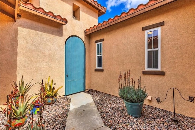 entrance to property featuring a tile roof and stucco siding