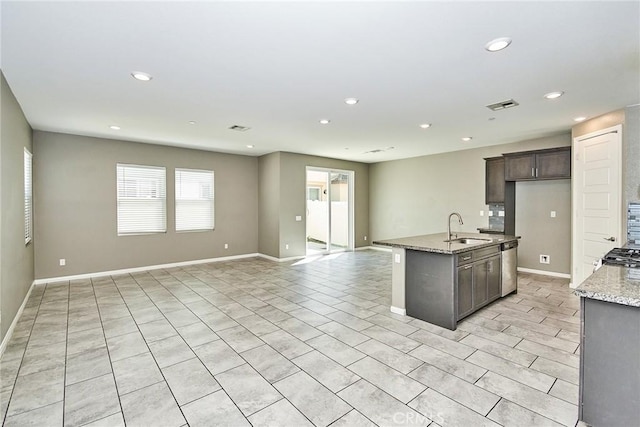 kitchen featuring a kitchen island with sink, a sink, visible vents, open floor plan, and stainless steel dishwasher