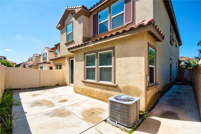 rear view of property with a patio area, central AC, a fenced backyard, and stucco siding