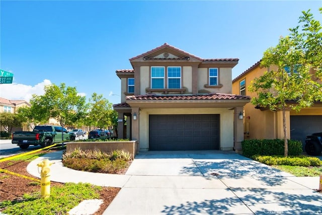 mediterranean / spanish-style home featuring a garage, a tile roof, concrete driveway, and stucco siding