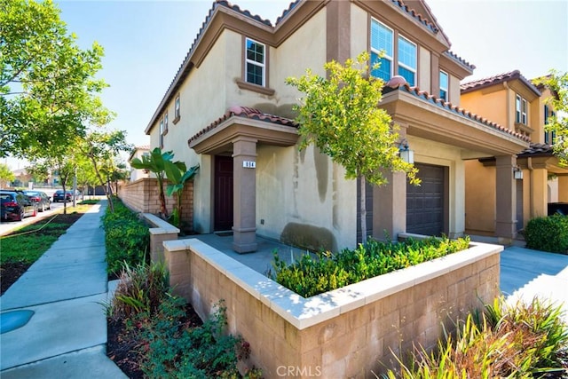 mediterranean / spanish-style home featuring a garage, a tile roof, and stucco siding