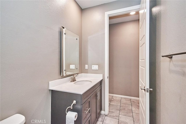 bathroom with toilet, tile patterned flooring, baseboards, and vanity