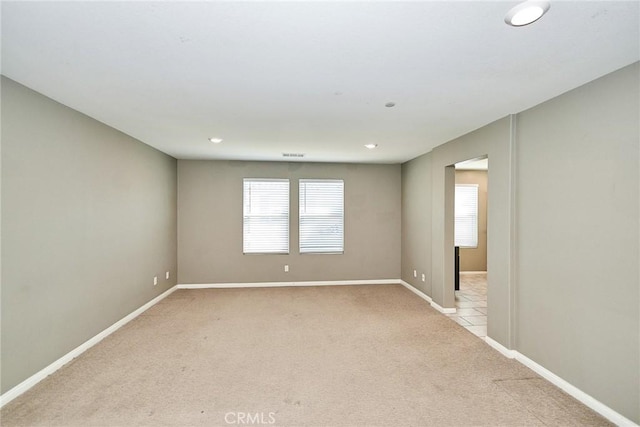 spare room featuring recessed lighting, light carpet, visible vents, and baseboards