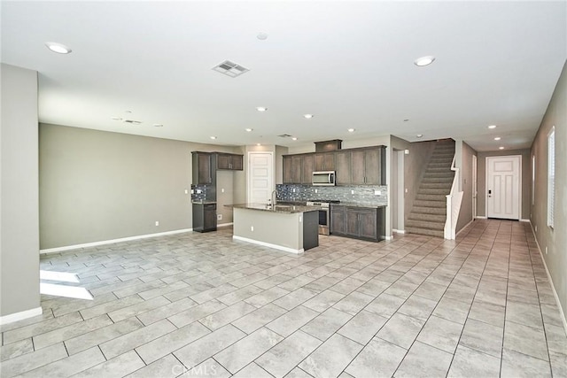 kitchen with visible vents, decorative backsplash, an island with sink, open floor plan, and stainless steel appliances