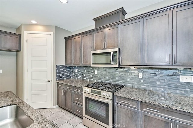 kitchen with light stone counters, stainless steel appliances, recessed lighting, tasteful backsplash, and dark brown cabinetry