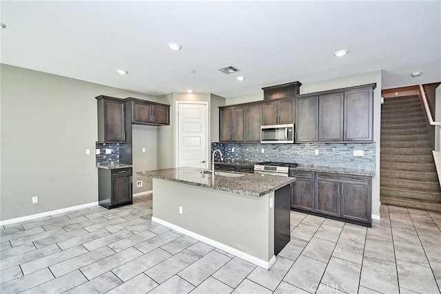 kitchen with visible vents, appliances with stainless steel finishes, light stone counters, dark brown cabinets, and a sink