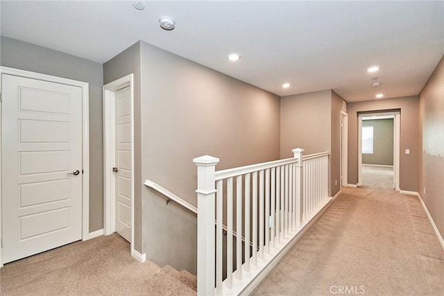 corridor featuring carpet floors, recessed lighting, baseboards, and an upstairs landing