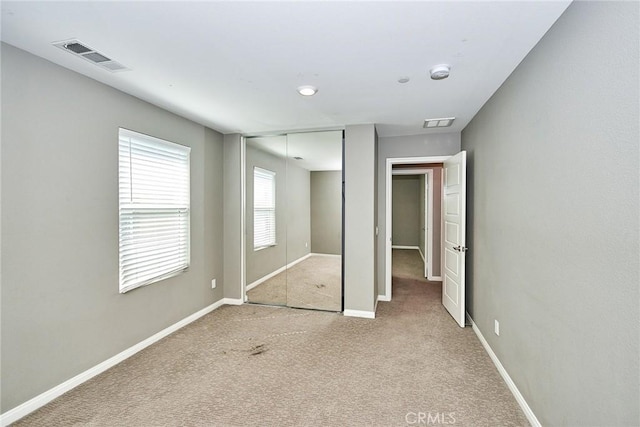 unfurnished bedroom with carpet, a closet, visible vents, and baseboards