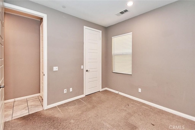 unfurnished bedroom featuring carpet, visible vents, baseboards, and tile patterned floors