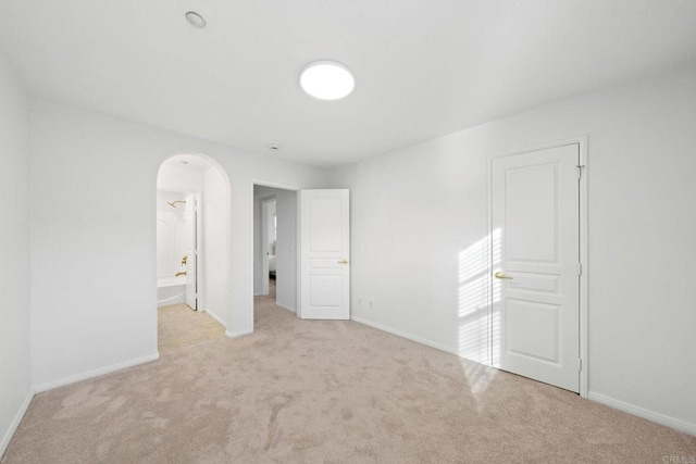 unfurnished bedroom featuring carpet floors, baseboards, and arched walkways