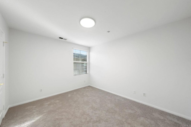 carpeted spare room featuring visible vents and baseboards