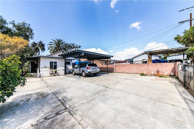 exterior space featuring a carport, fence, and concrete driveway