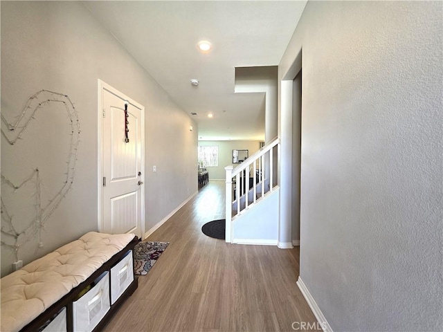 hall with stairway, wood finished floors, and baseboards