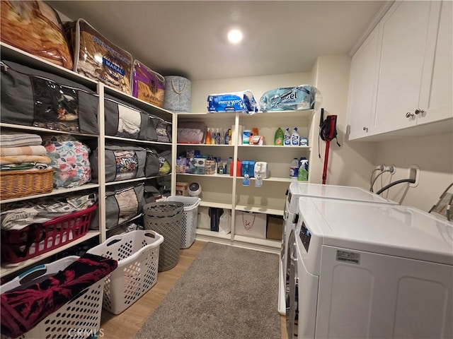 washroom featuring light wood finished floors, independent washer and dryer, and cabinet space