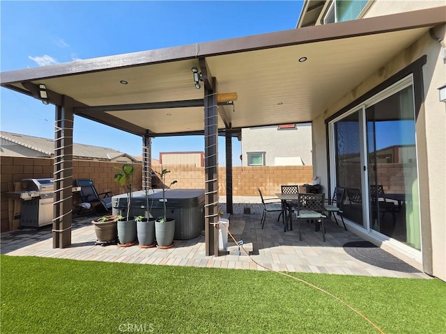 view of patio with fence private yard, a hot tub, and grilling area