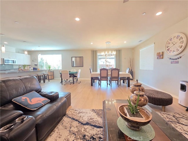 living room featuring recessed lighting, baseboards, a notable chandelier, and light wood finished floors