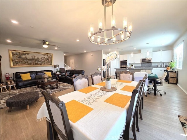 dining area with light wood-style floors, stairs, ceiling fan with notable chandelier, and recessed lighting