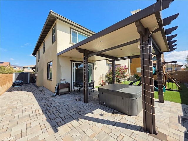 view of patio / terrace featuring a playground, a hot tub, and a fenced backyard