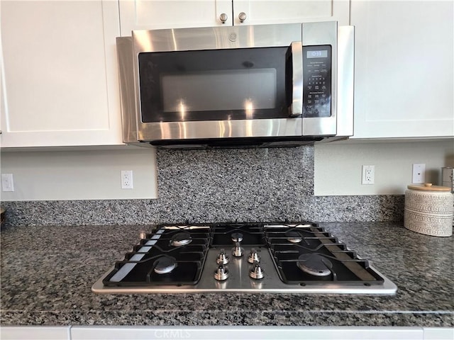 details with stainless steel appliances, dark stone countertops, white cabinets, and decorative backsplash