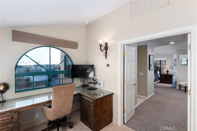 office with baseboards, visible vents, light colored carpet, lofted ceiling, and built in desk