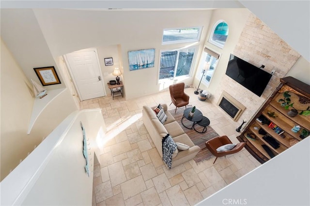 living room with a glass covered fireplace, a high ceiling, and stone tile floors