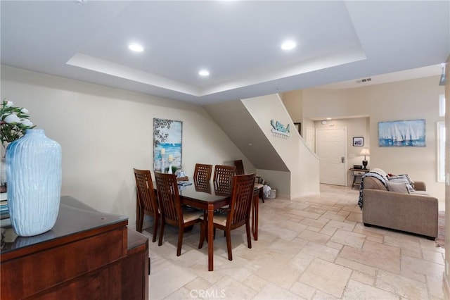 dining space with visible vents, a tray ceiling, stone tile flooring, and recessed lighting