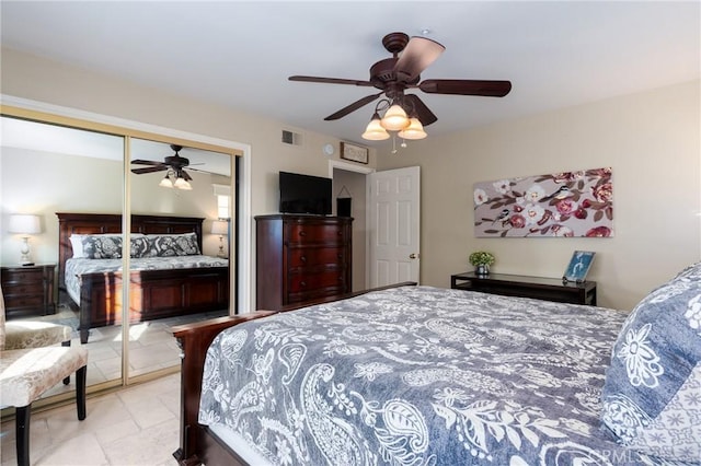 bedroom featuring a closet, visible vents, ceiling fan, and stone tile floors