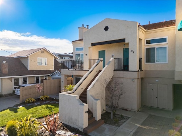 exterior space with stairs, a chimney, fence, and stucco siding