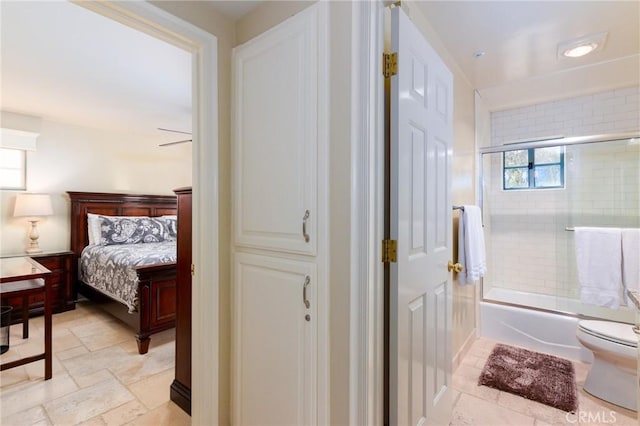 ensuite bathroom featuring shower / bath combination with glass door, ensuite bath, toilet, and stone tile floors