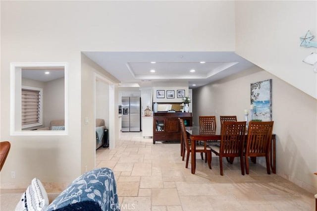 dining area with baseboards, a tray ceiling, stone tile flooring, and recessed lighting